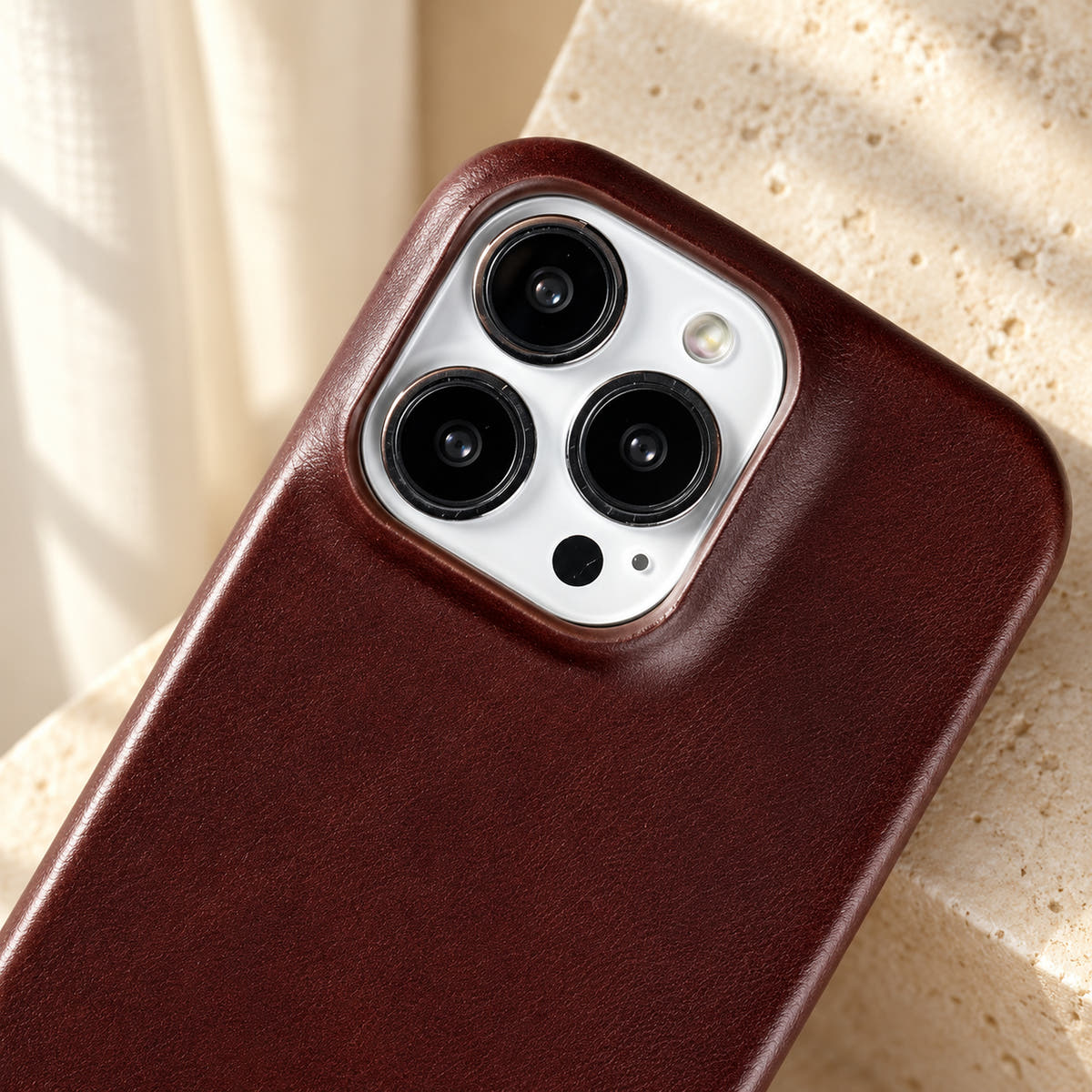 Minimal leather-look iPhone case in Burgundy, close-up of the matching camera border.