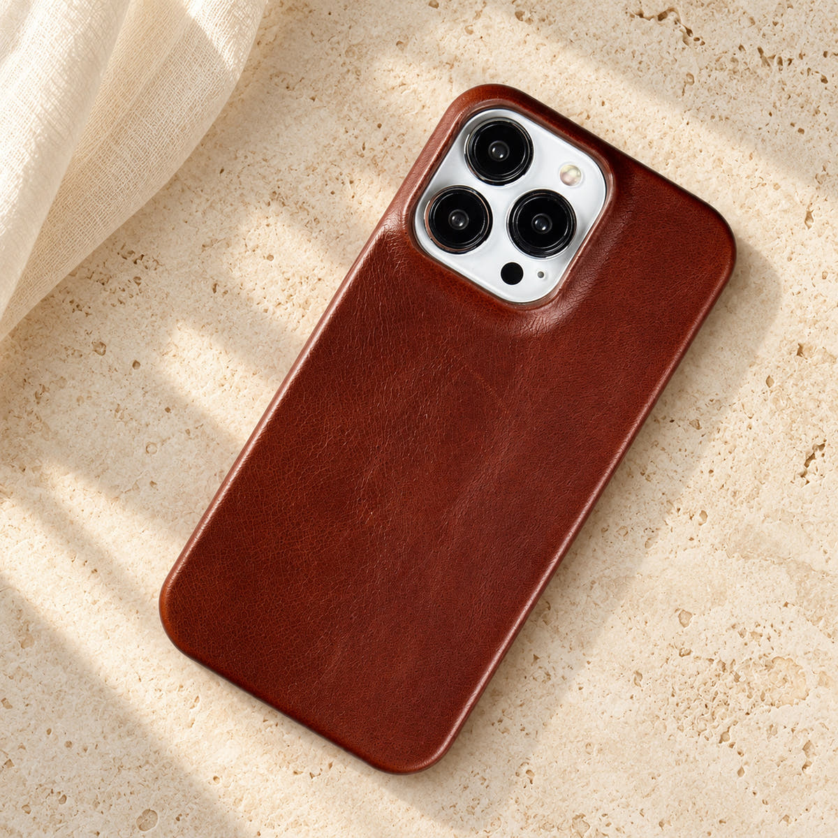 Minimal leather-look iPhone case in Dark Brown, full rear view on an ivory tabletop.