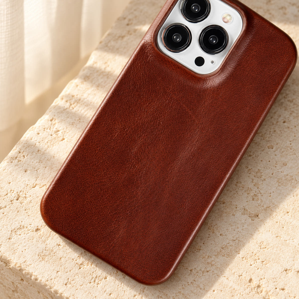 Minimal leather-look iPhone case in Dark Brown, close-up of the fine-grained back and rounded corners.