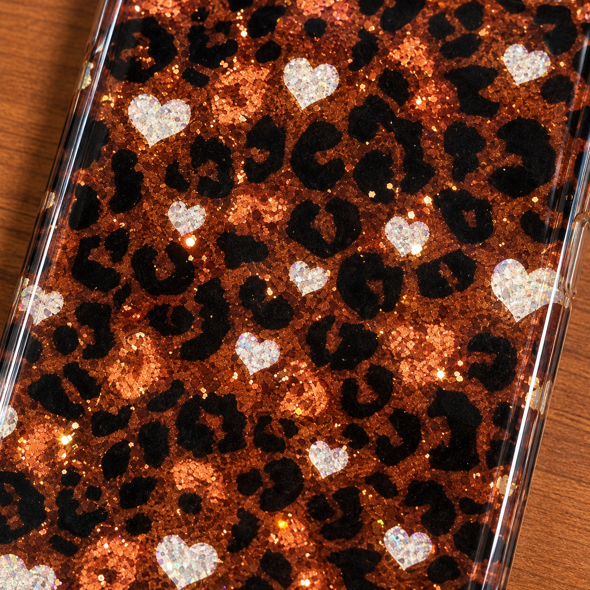 Close-up of pale sparkling hearts, black leopard print and warm light-catching flecks on the Amber Leopard Heart case.