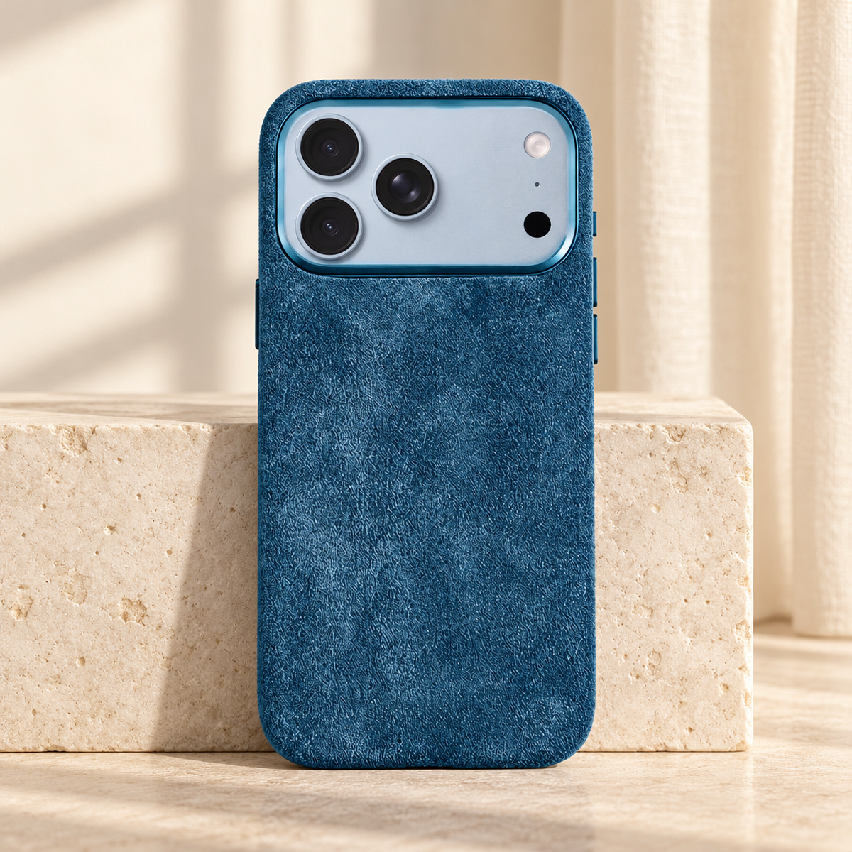 Ocean Blue suede-look textured iPhone case shown upright beside a pale stone block.