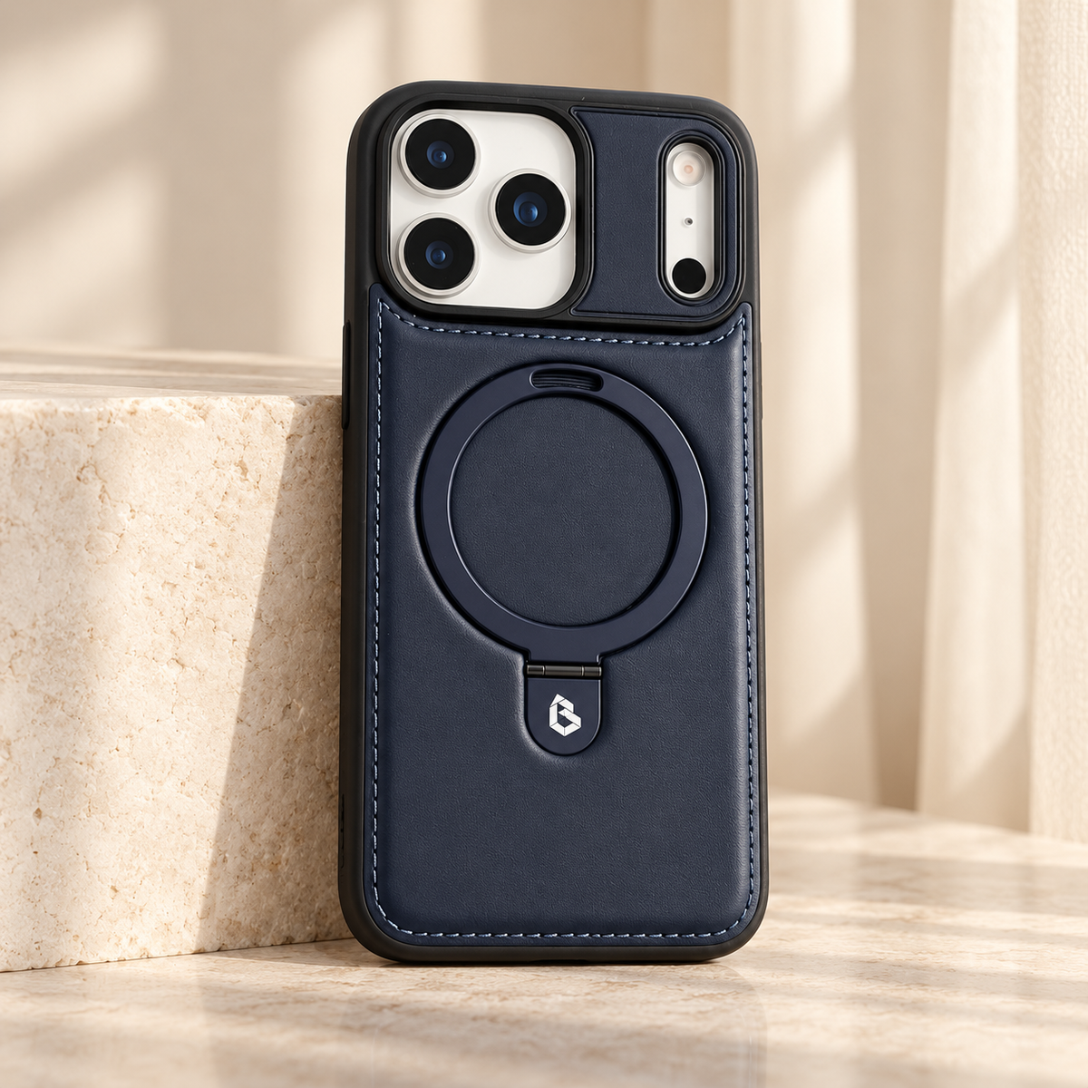 Navy stitched ring-stand iPhone case shown upright beside a pale stone block.