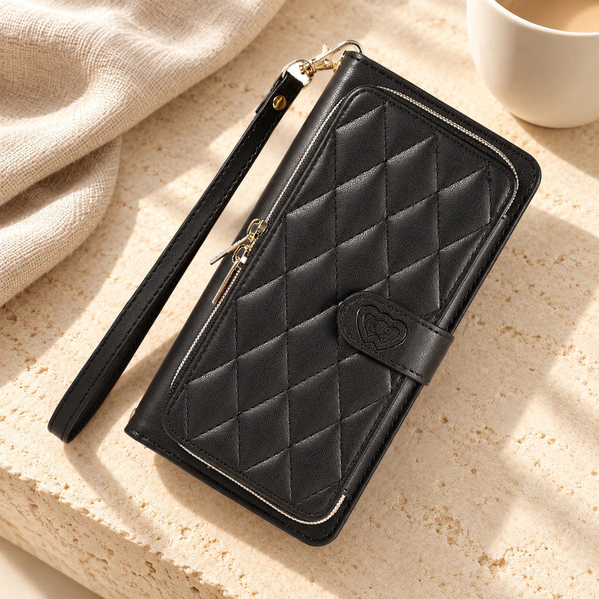 Black padded zip wallet with wrist strap in a neutral tabletop setting
