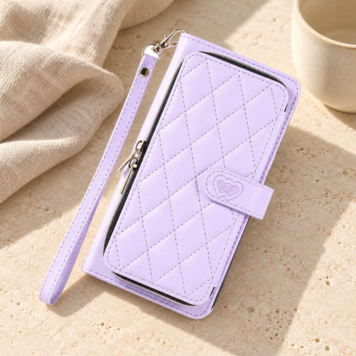 Lavender padded zip wallet with wrist strap in a neutral tabletop setting