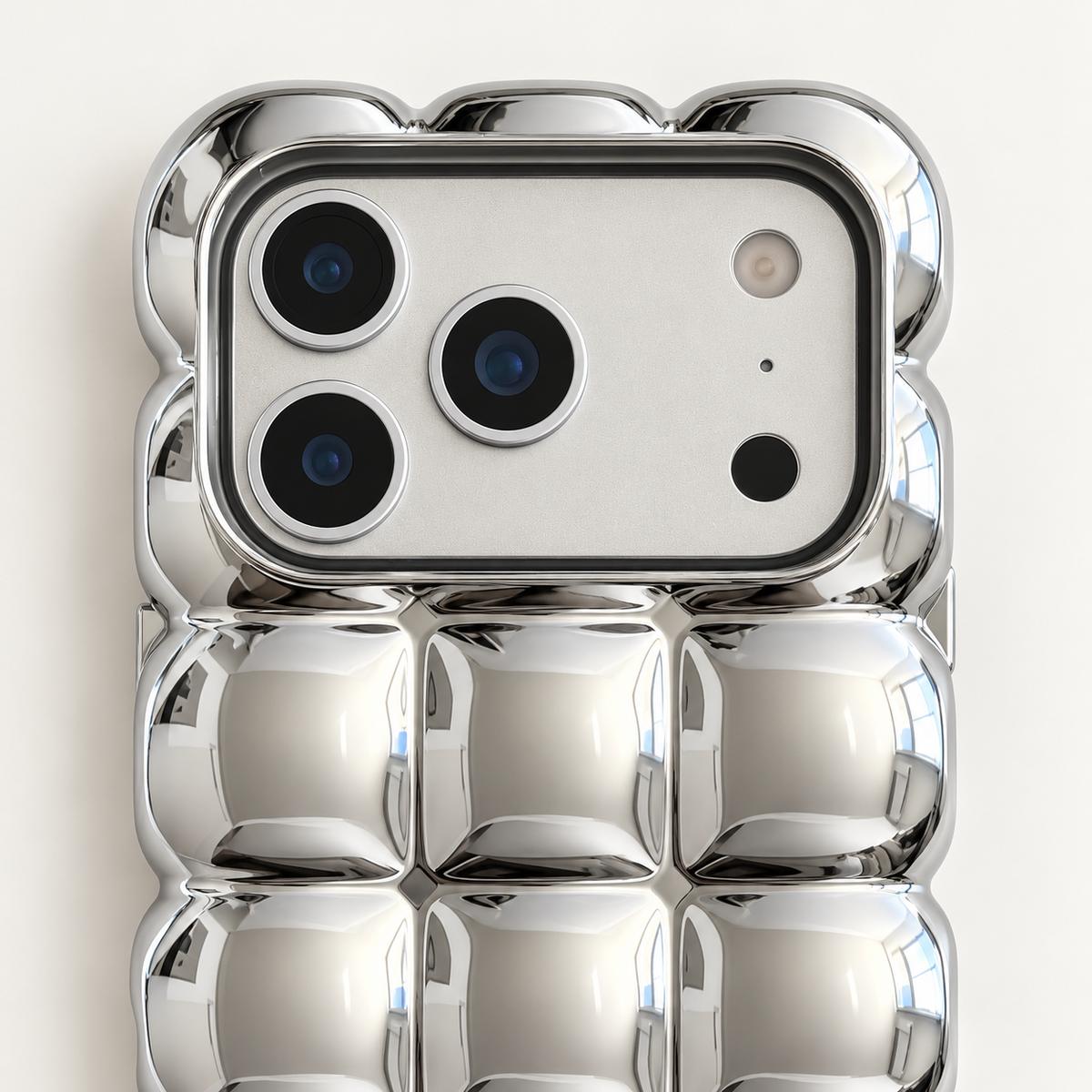 Mirror Silver puffy grid iPhone case with rounded-square back and scalloped edges — close-up of camera surround and sculpted grid.