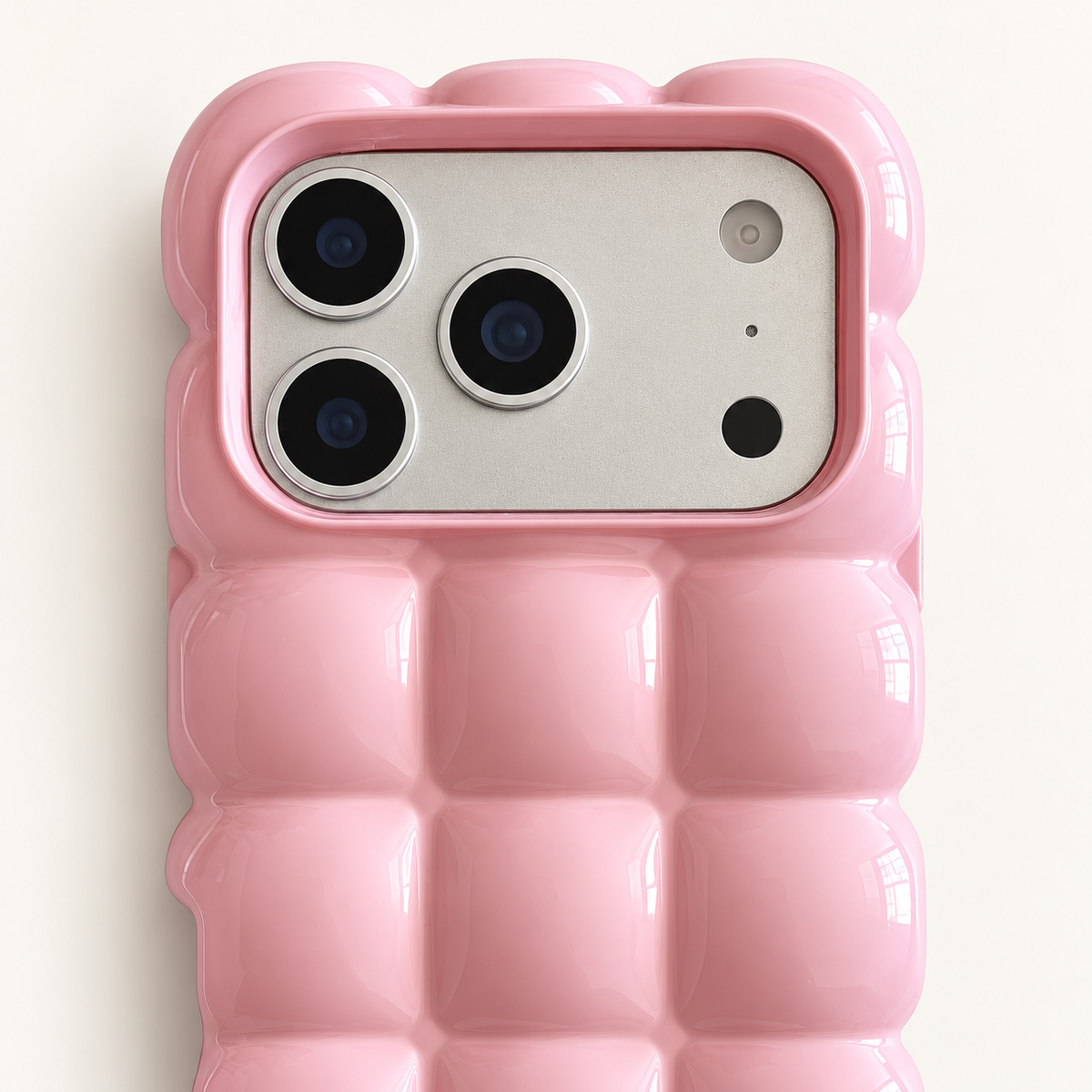 Pink puffy grid iPhone case with rounded-square back and scalloped edges — close-up of camera surround and sculpted grid.
