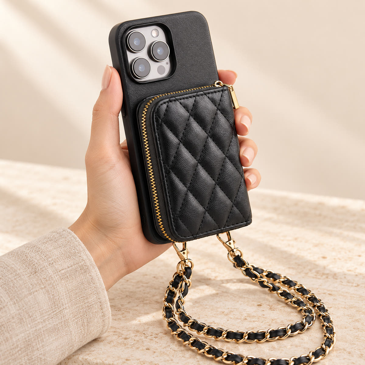 Black quilted iPhone wallet case — handheld view with zip wallet and chain