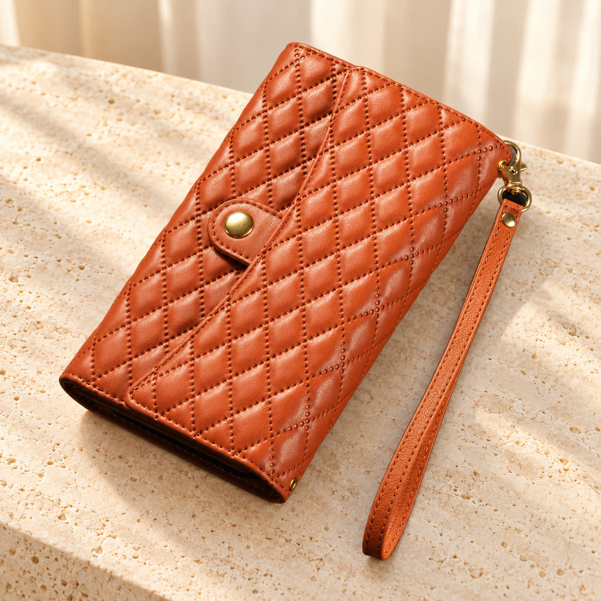 Quilted Zip Wallet iPhone case in Brown on cream limestone, with the closed diamond-quilted front, snap flap and matching wrist loop.