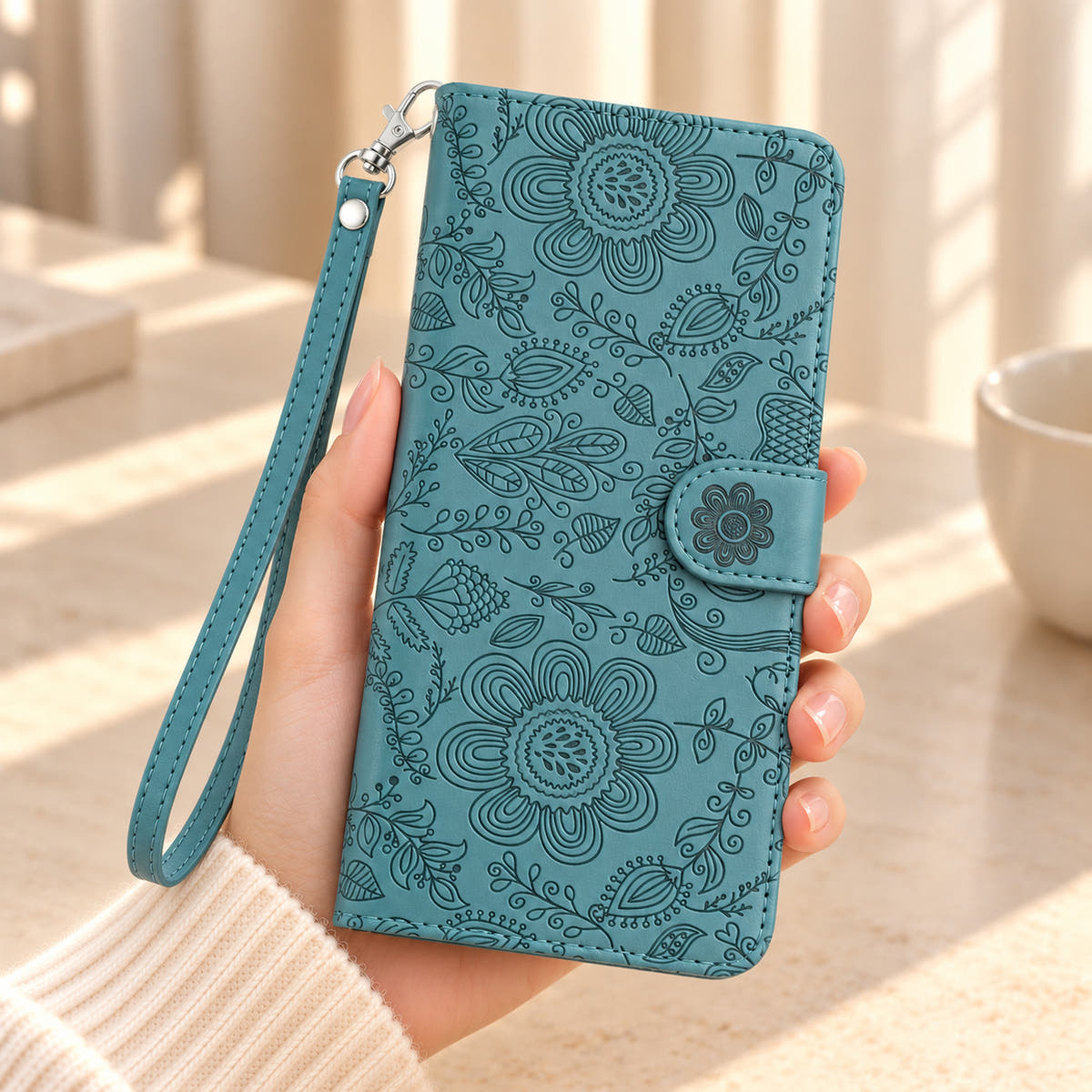ScarletBloom Forest Green floral wallet phone case held in a hand, showing the embossed cover, flower closure tab and matching wrist loop.
