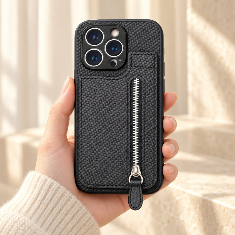Signature Black iPhone wallet case held in a cream-sleeved hand, showing its textured rear panel and zip pocket.
