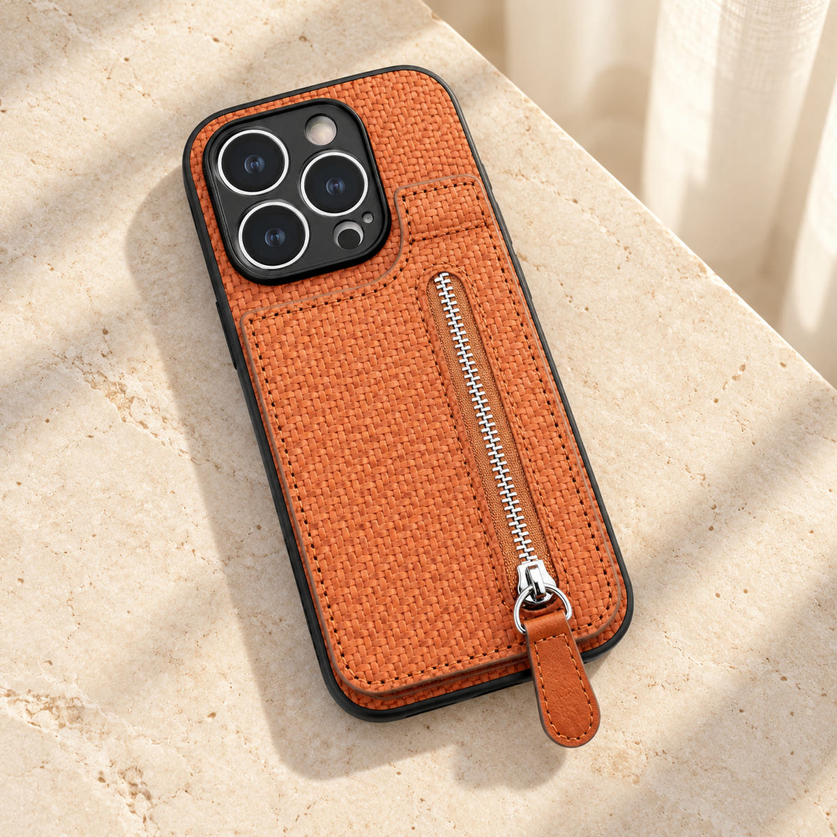 Signature Brown iPhone wallet case resting on cream limestone with its complete textured back and silver-tone zipper visible.