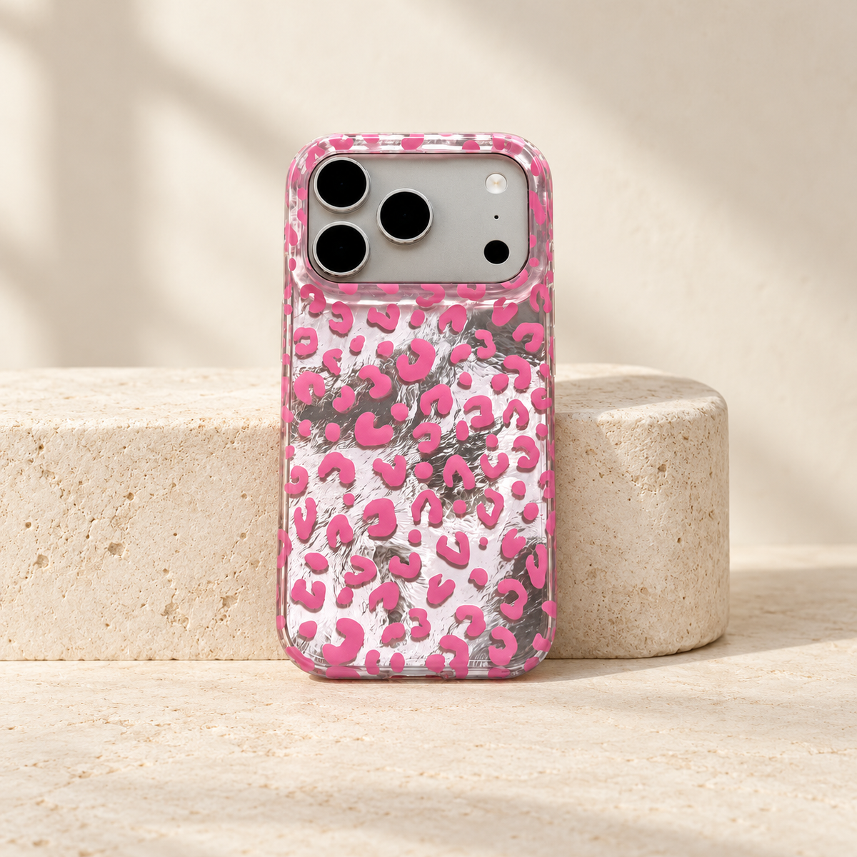 Full rear view of the Pink leopard iPhone case standing against a small cream stone block.