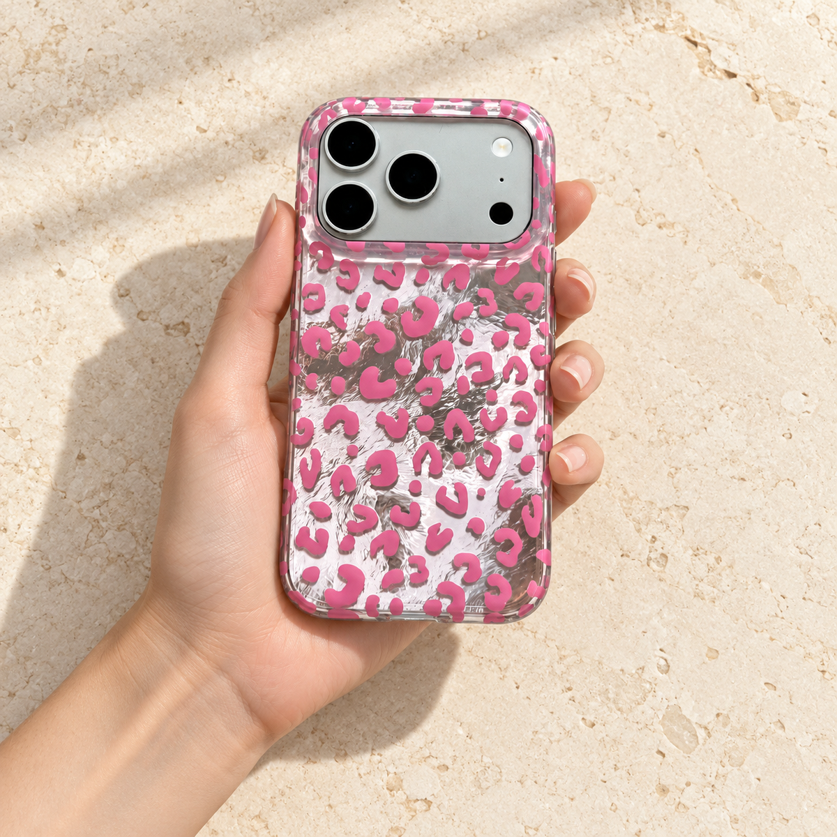 Pink leopard iPhone case resting flat in one hand, viewed from above.