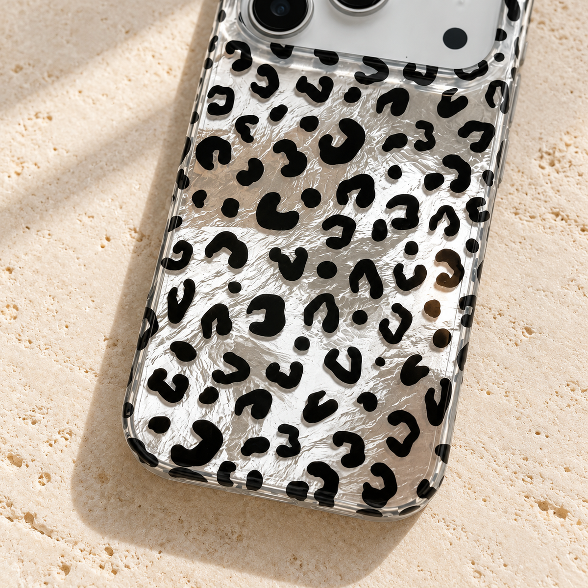 Black leopard print and crinkled silver finish in close-up with the rounded clear lower edge.