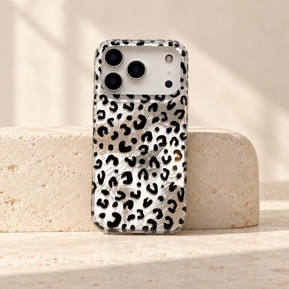 Full rear view of the Black leopard iPhone case standing against a cream stone block.