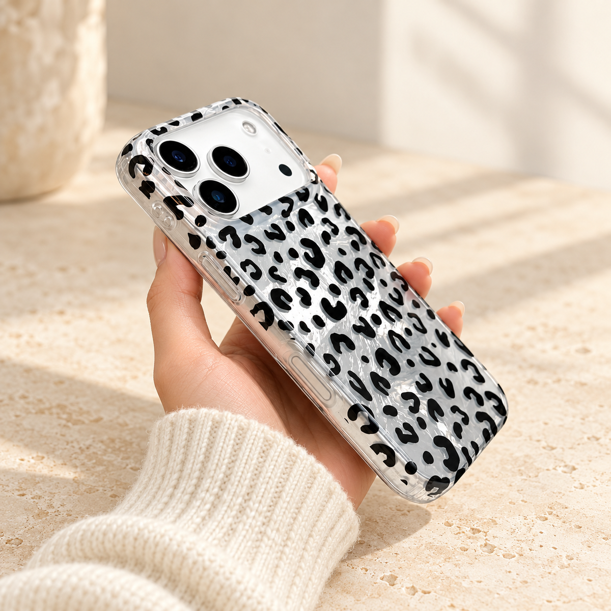 Black leopard iPhone case held at an angle showing its clear side-button covers and silver-effect back.