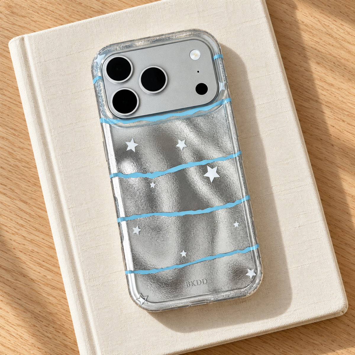 Silver Star Wave case styled on a plain cream notebook with the complete star-and-wave pattern visible.
