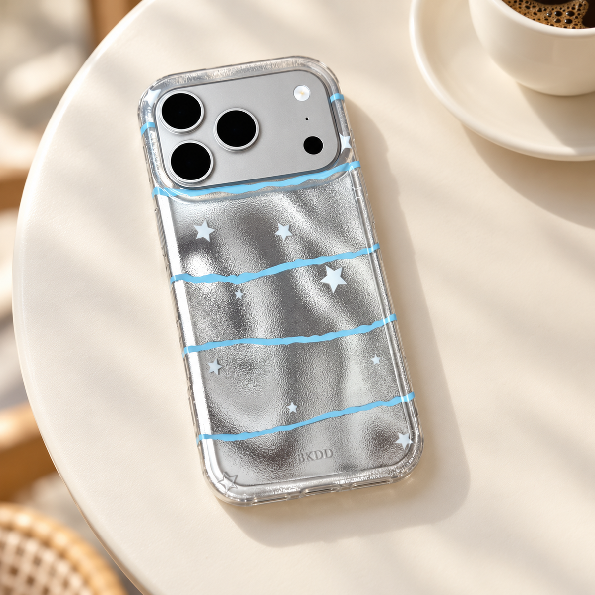 Silver Star Wave case resting on a cream café table with an ivory cup softly blurred in the background.