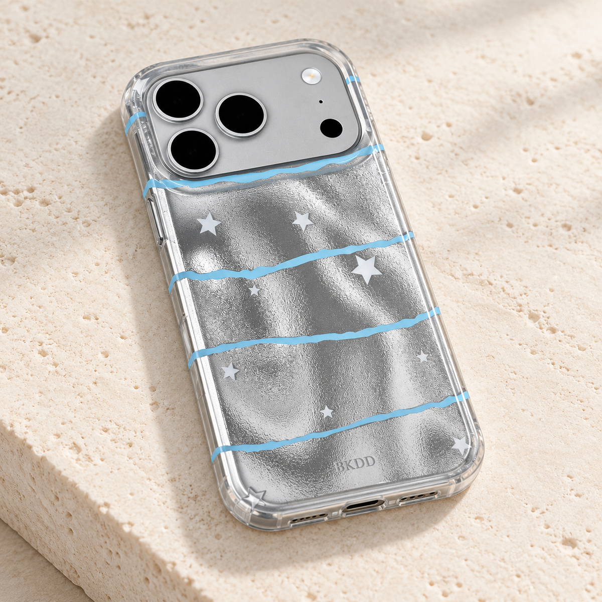 Low angled view of the Silver Star Wave case on a cream stone plinth, showing its clear edge and reflective patterned back.