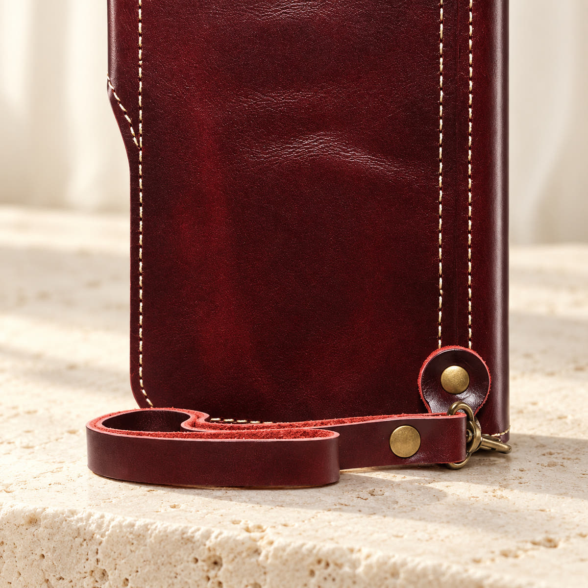 Red wallet case wrist-loop detail showing the matching loop, clip and riveted rear attachment