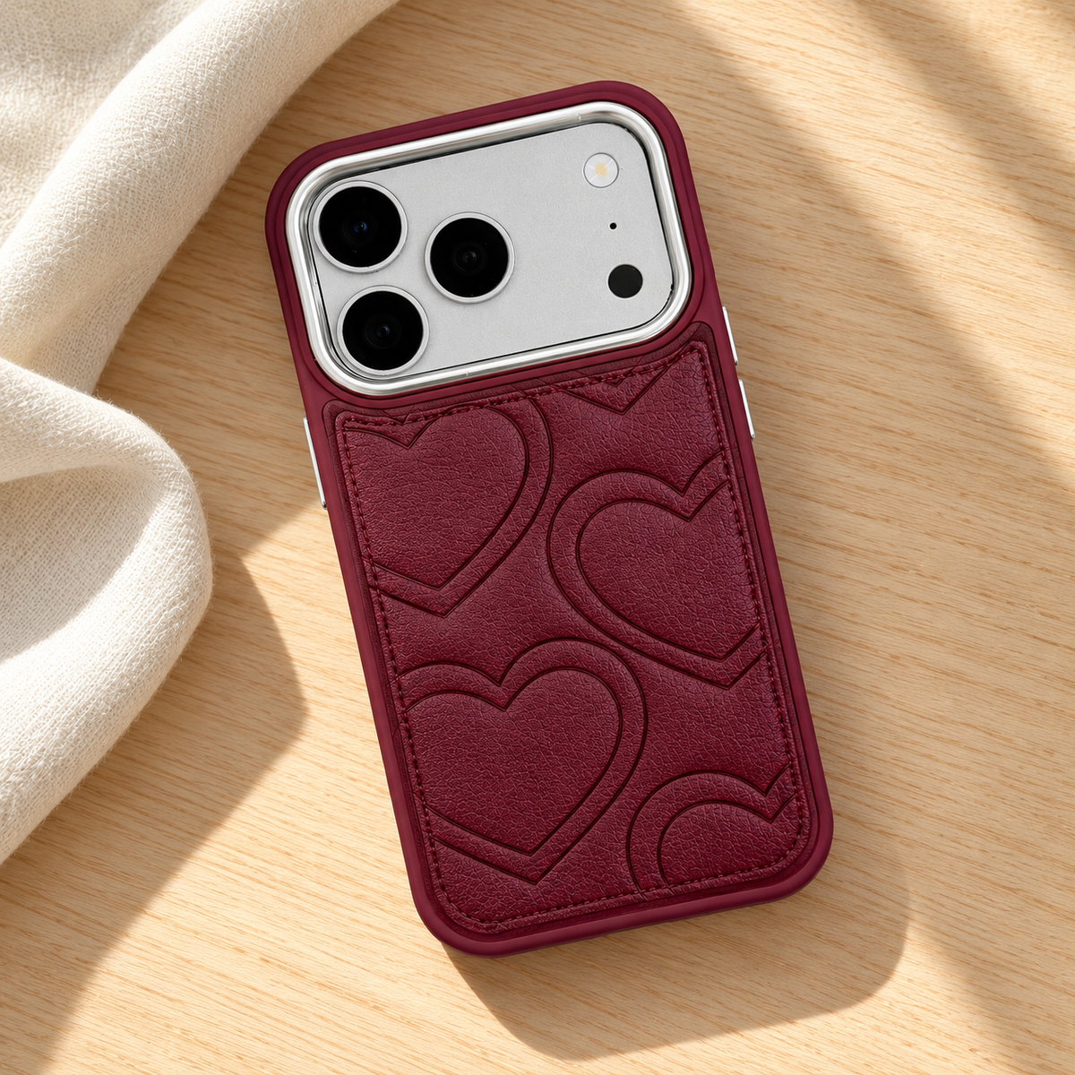 Textured heart iPhone case in Burgundy — diagonal tabletop view.