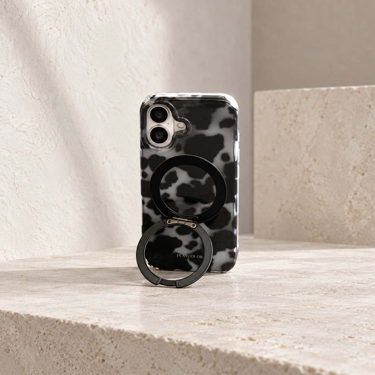 Grey tortoiseshell iPhone case standing vertically on its fold-out black rear ring.