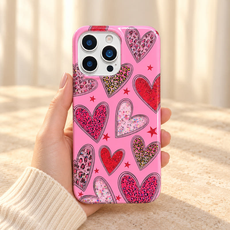 Valentina Sparkle Heart iPhone case in Pink held in a cream-sleeved hand, showing the complete glitter heart and star design.