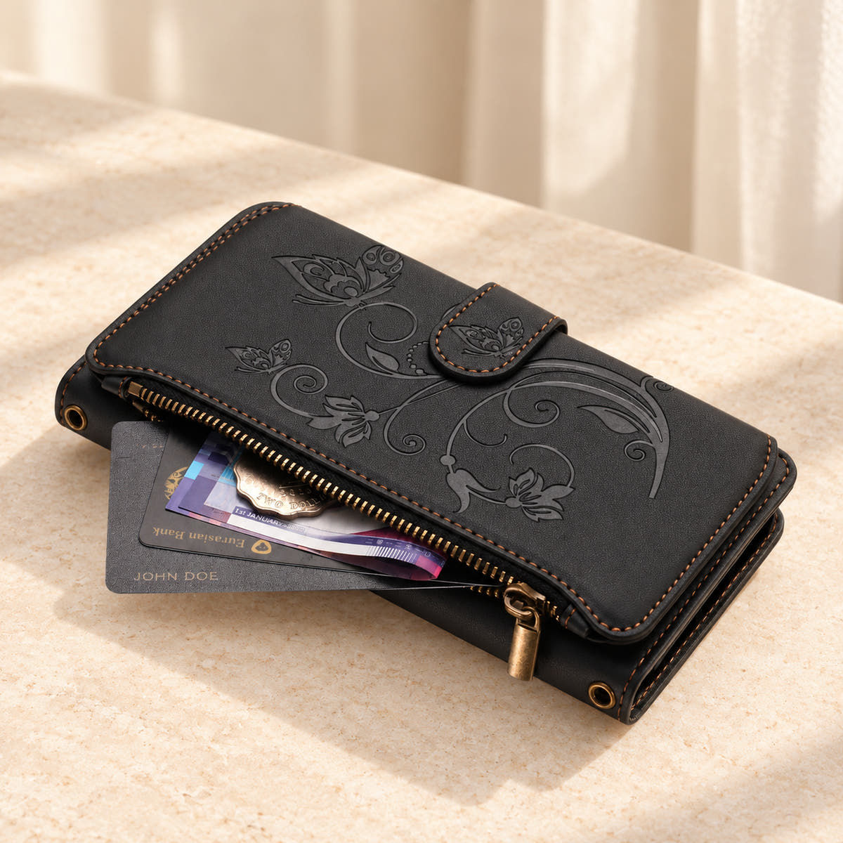 Velora Zip wallet case in Black on cream limestone, showing the embossed front and open side zip pocket with cards and cash.