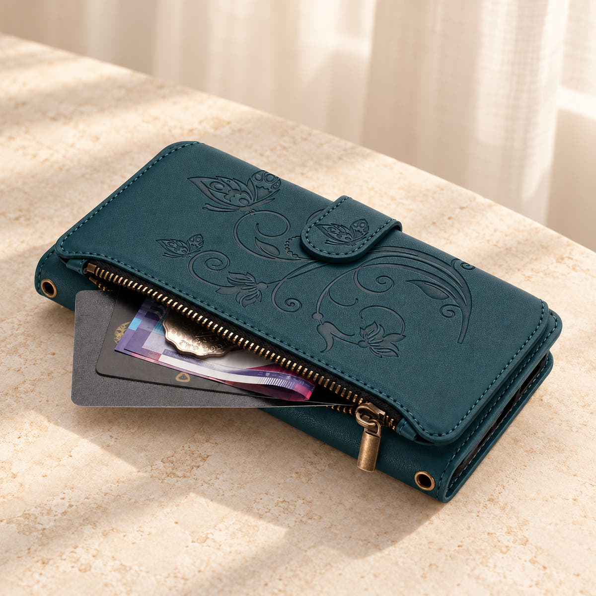 Velora Zip wallet case in Forest Green on cream limestone, showing the embossed front and open side zip pocket with cards and cash.