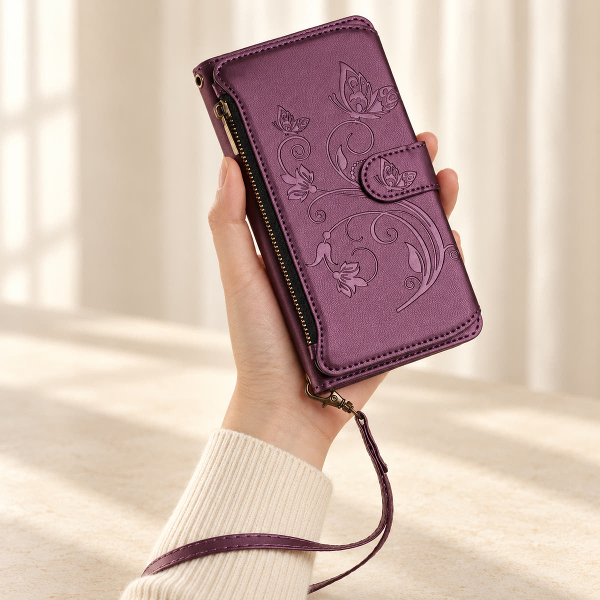 Velora Zip iPhone wallet case in Plum, handheld with embossed butterfly front, side zip and matching wrist strap.