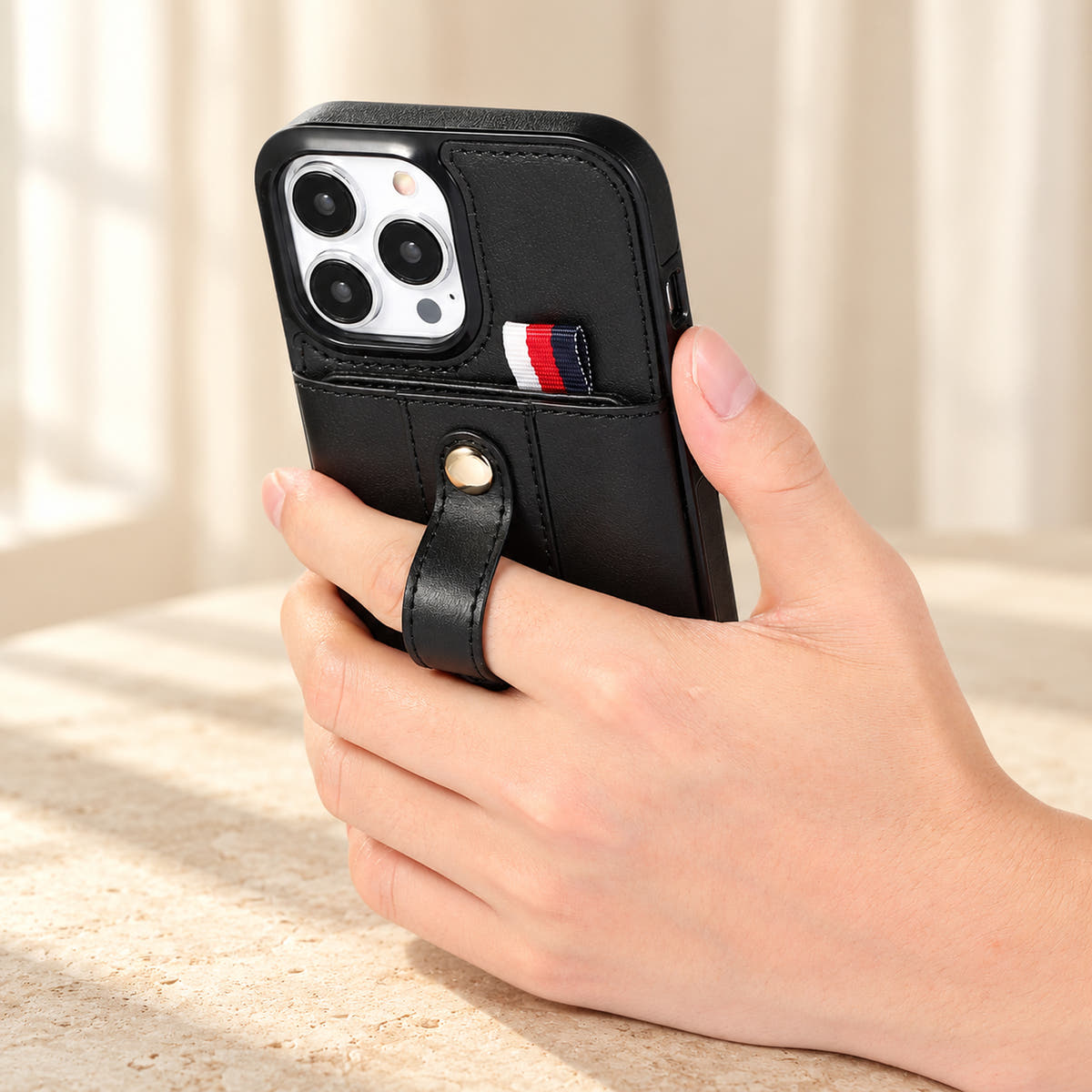 Black iPhone wallet case with card pocket and adjustable hand strap, handgrip